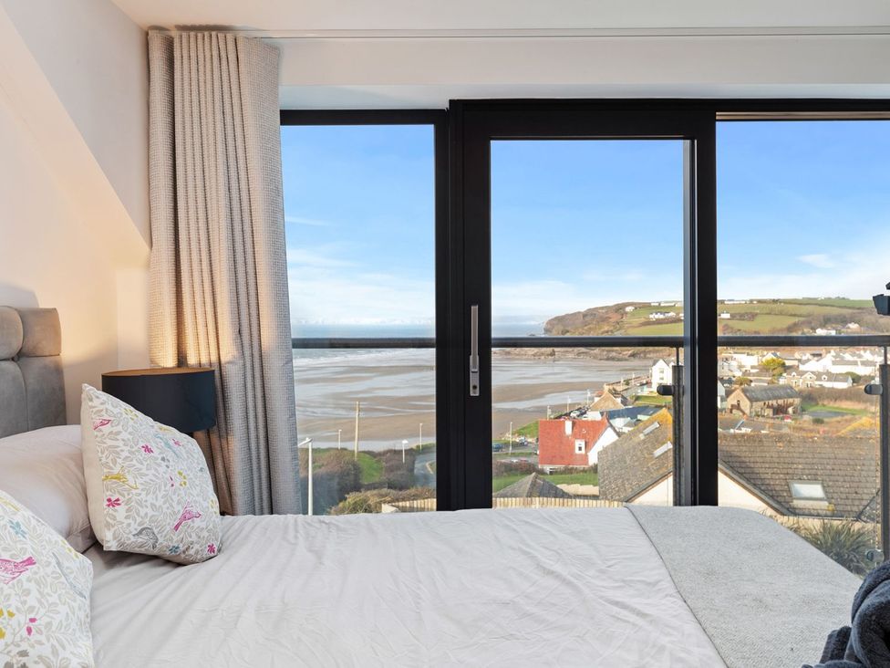 A bedroom with a view of the coastline at One Sand Banks in Haverfordwest
