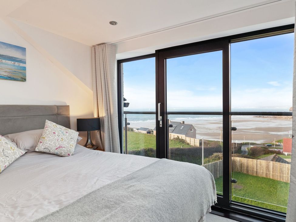 A bedroom with a bed and window overlooking the beach at One Sand Banks in Haverfordwest