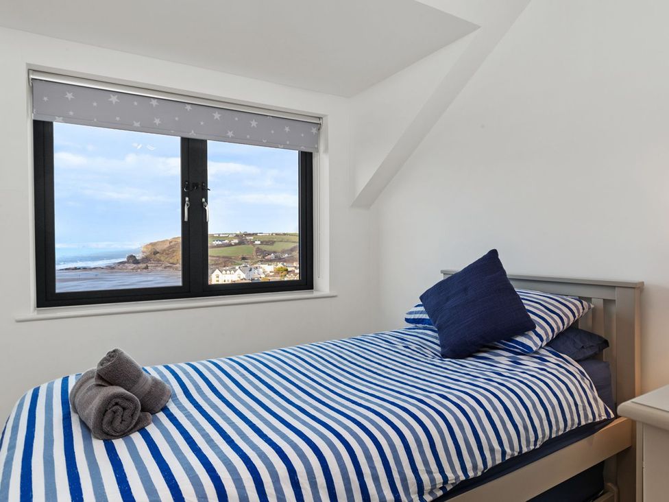 A bedroom with a view of the shoreline at One Sand Banks Haverfordwest