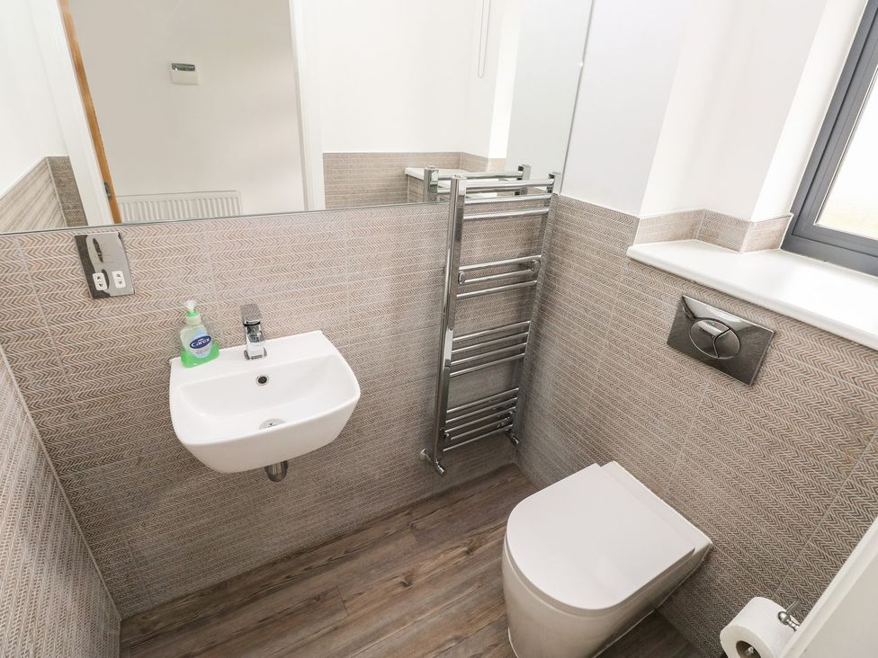 A bathroom with a sink, toilet, and towel radiator at One Sand Banks Haverfordwest