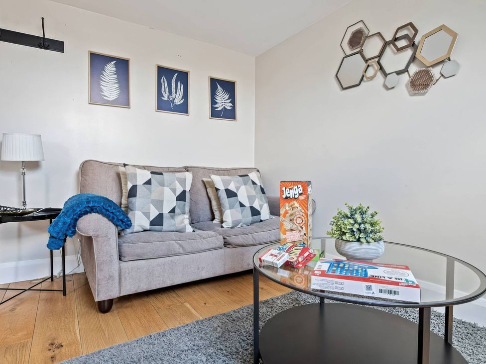 A living room with a sofa, games on a table and wall art at TBC 