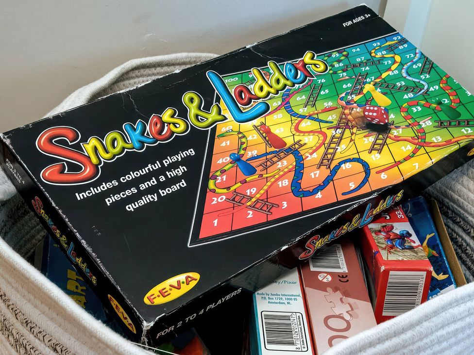 A box of Snakes and Ladders game with colorful board and game pieces