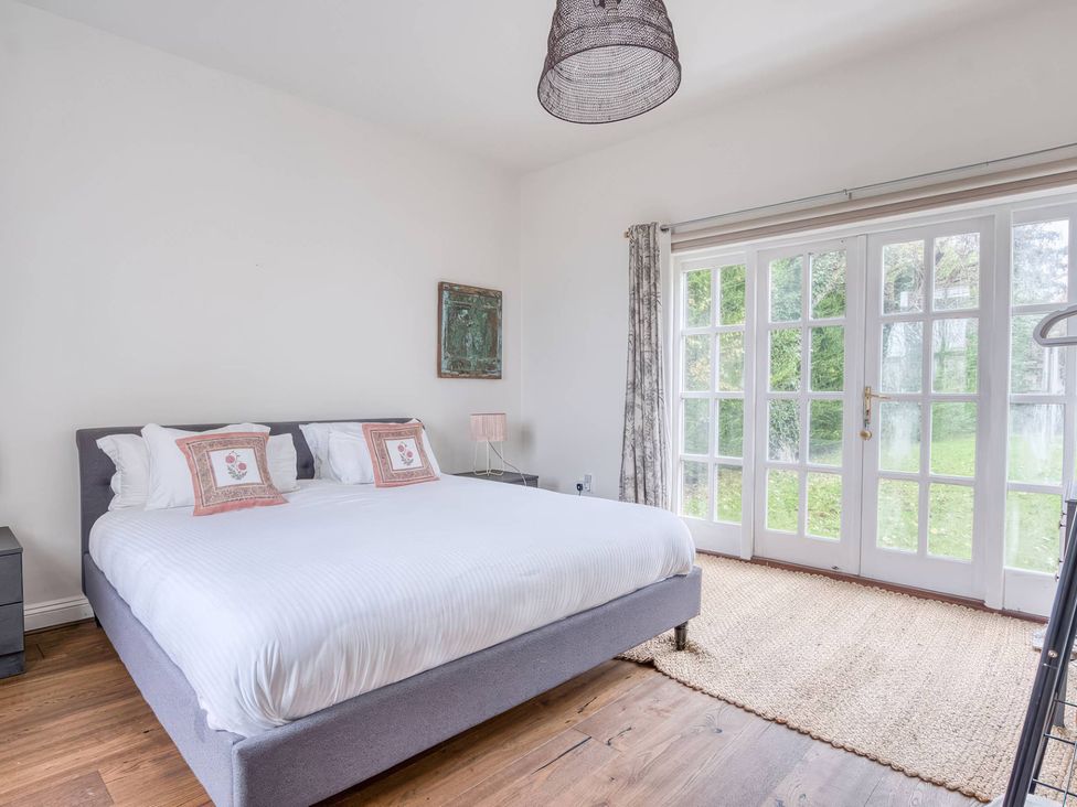 A bedroom with a bed, nightstand, lamp, and windows at TBC