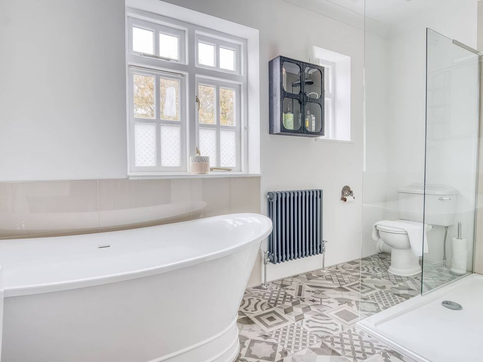 A bathroom with a bathtub, toilet, and shower at TBC