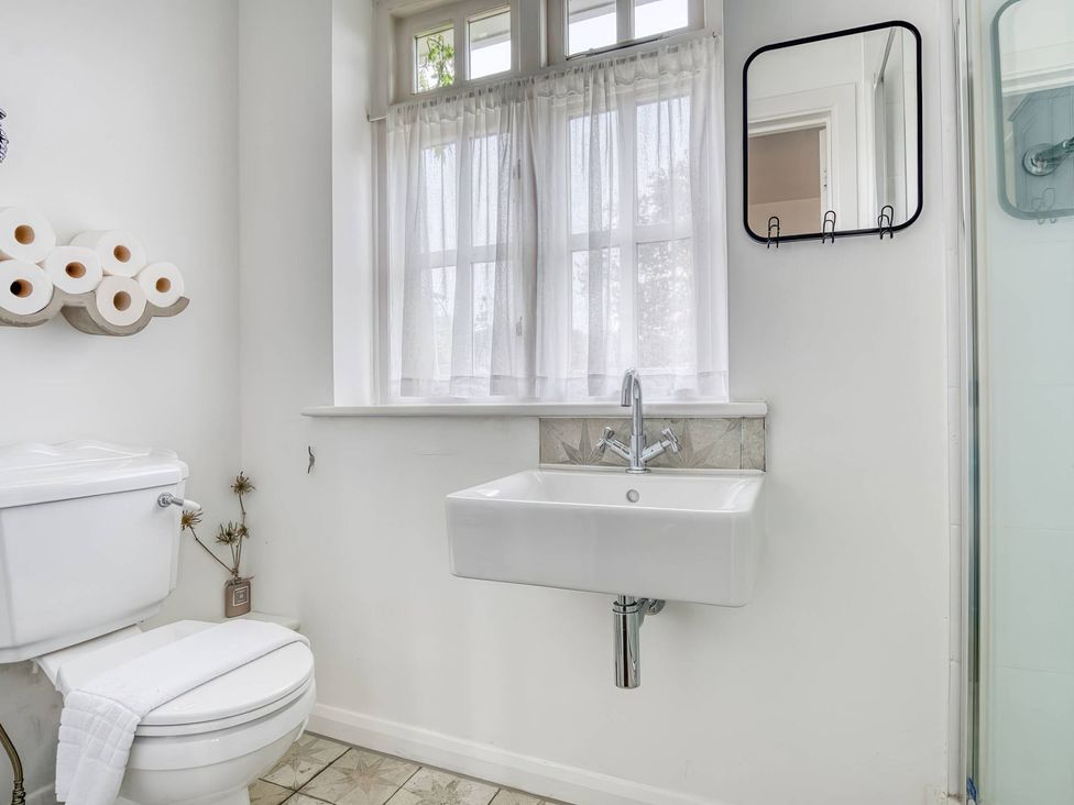 A bathroom featuring a toilet, sink, and mirror at TBC