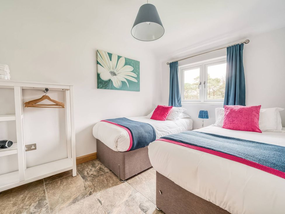 A bedroom with two beds and a white furniture shelf at TBC in 