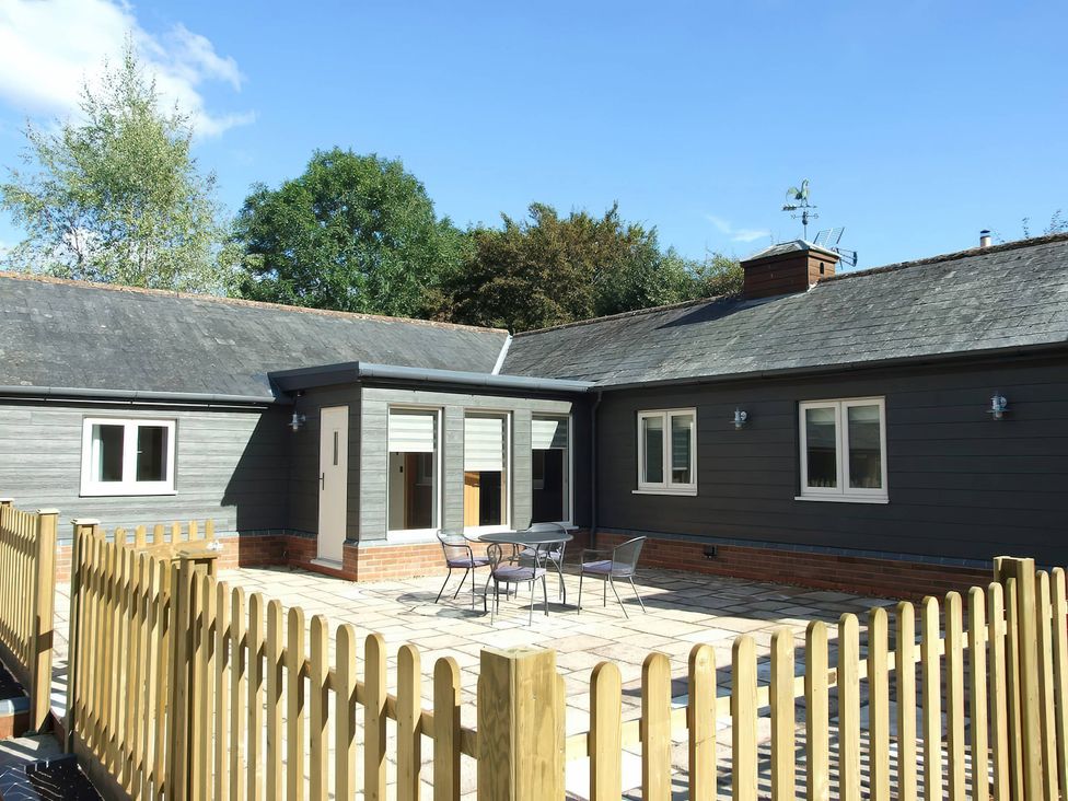 An outdoor area with a table and chairs next to a house at TBC 