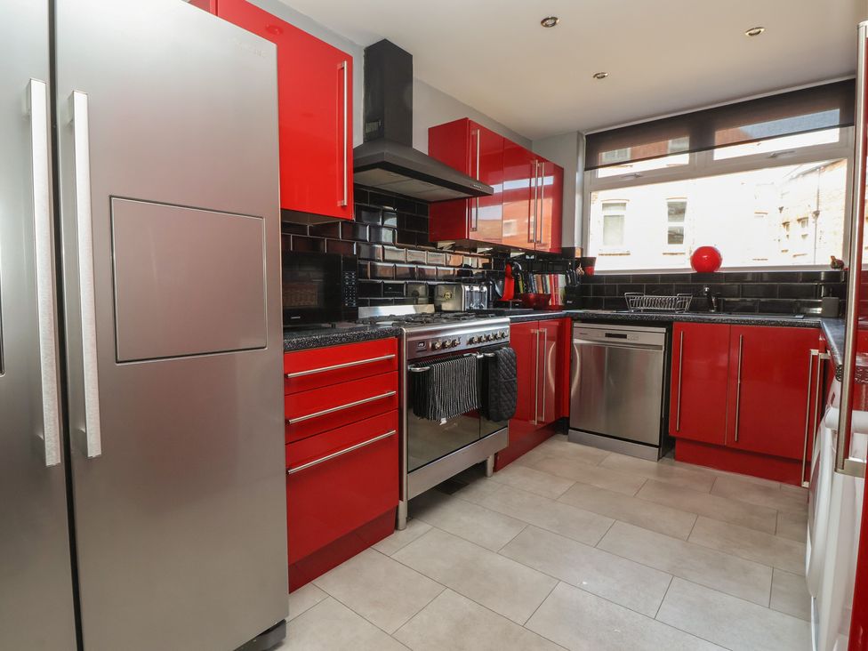 A kitchen with appliances and red cabinets at Tapestry House in Bridlington