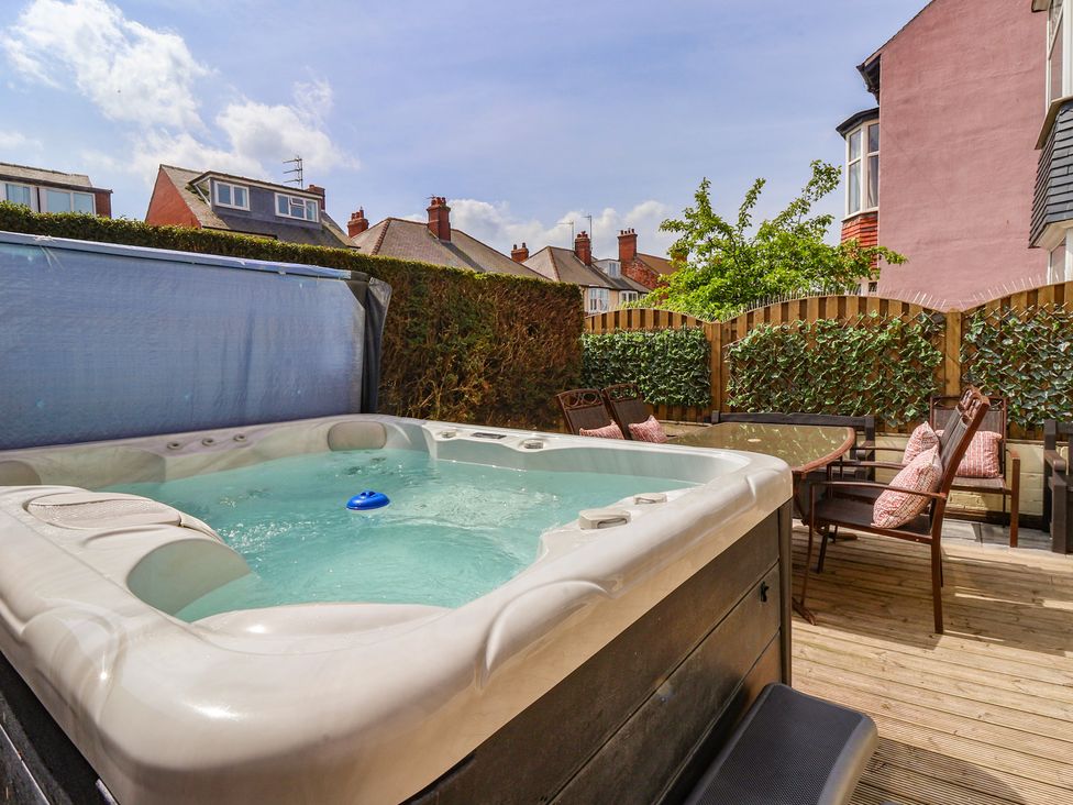 An outdoor patio with a hot tub and seating area at Tapestry House in Bridlington