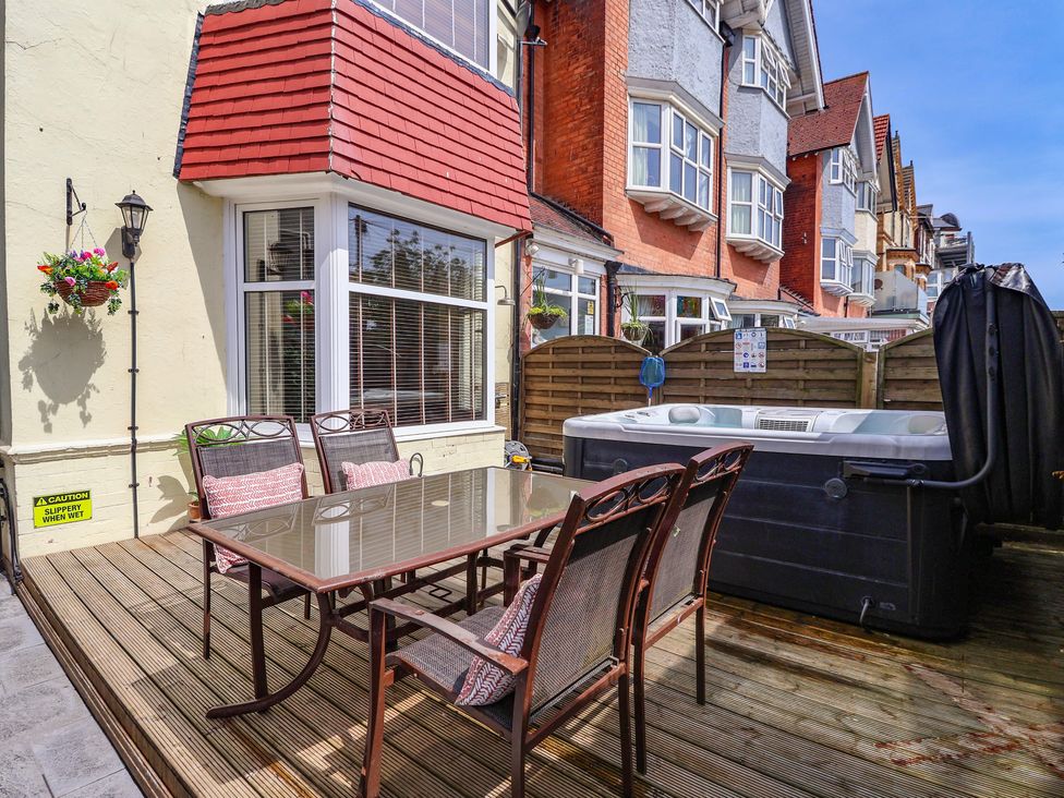 An outdoor patio with a table and chairs near a hot tub at Tapestry House in Bridlington