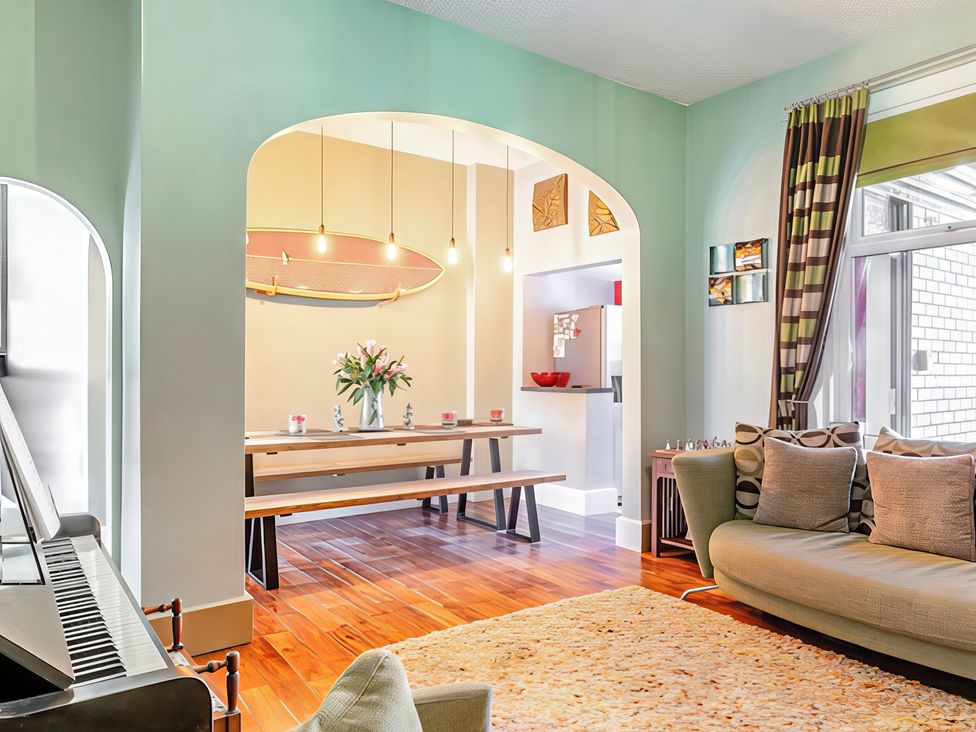 A living room with a piano and dining area at Tapestry House in Bridlington