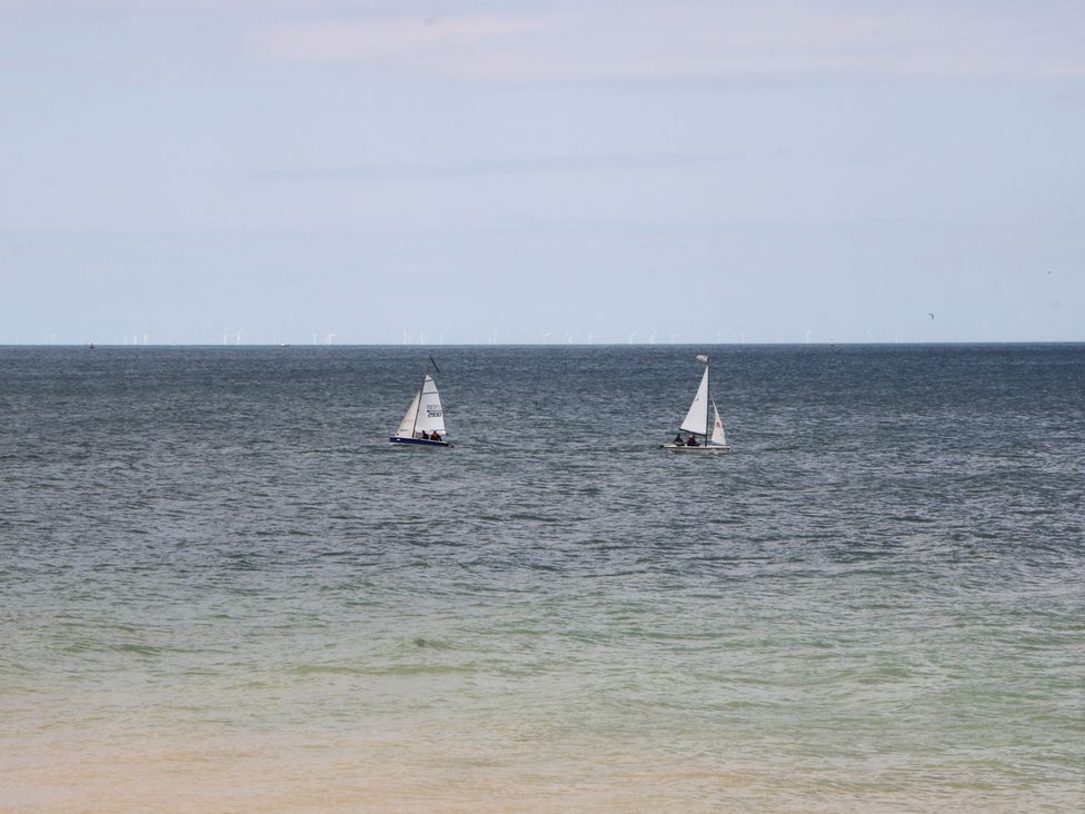 Two sailboats on the ocean with wind turbines in the background at Foreshore, Deal