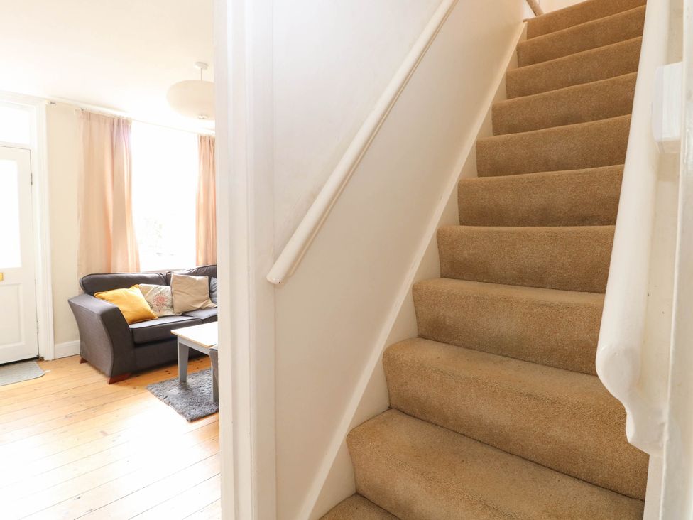 A staircase leading to the upper floor next to a living room with a sofa and coffee table at 19 Covert Road in Reydon