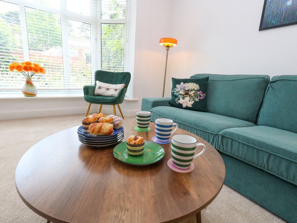 A living room with a green sofa and a coffee table with muffins and cups at 29 Bincleaves Road Weymouth