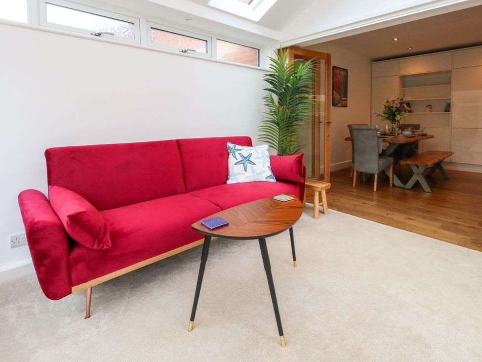 A living room with a red sofa and a dining area at 29 Bincleaves Road Weymouth
