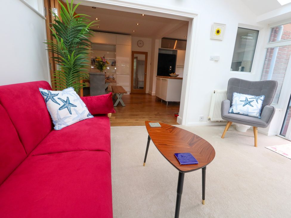 A snug with a red sofa, a chair, and a table at 29 Bincleaves Road Weymouth
