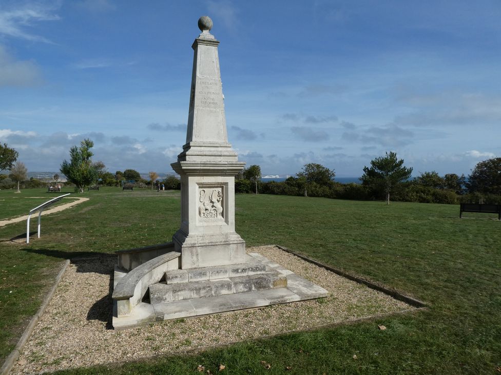 A monument with steps and plaque in a park setting at Coast Path Cottage Weymouth