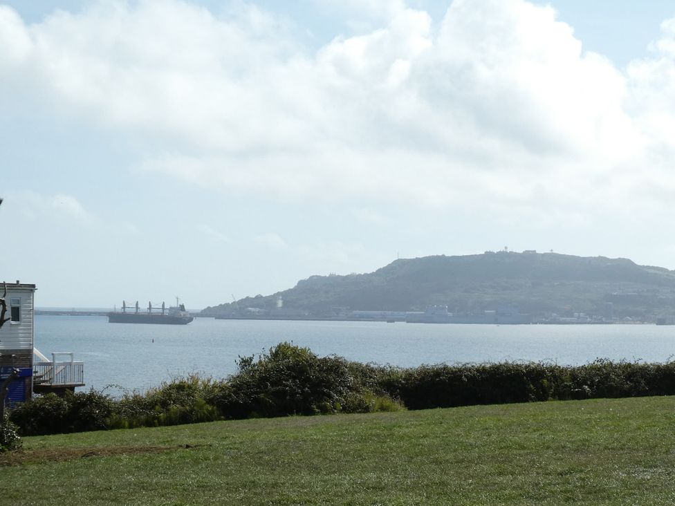 A view of a ship on water with a hill in the background at Coast Path Cottage Weymouth