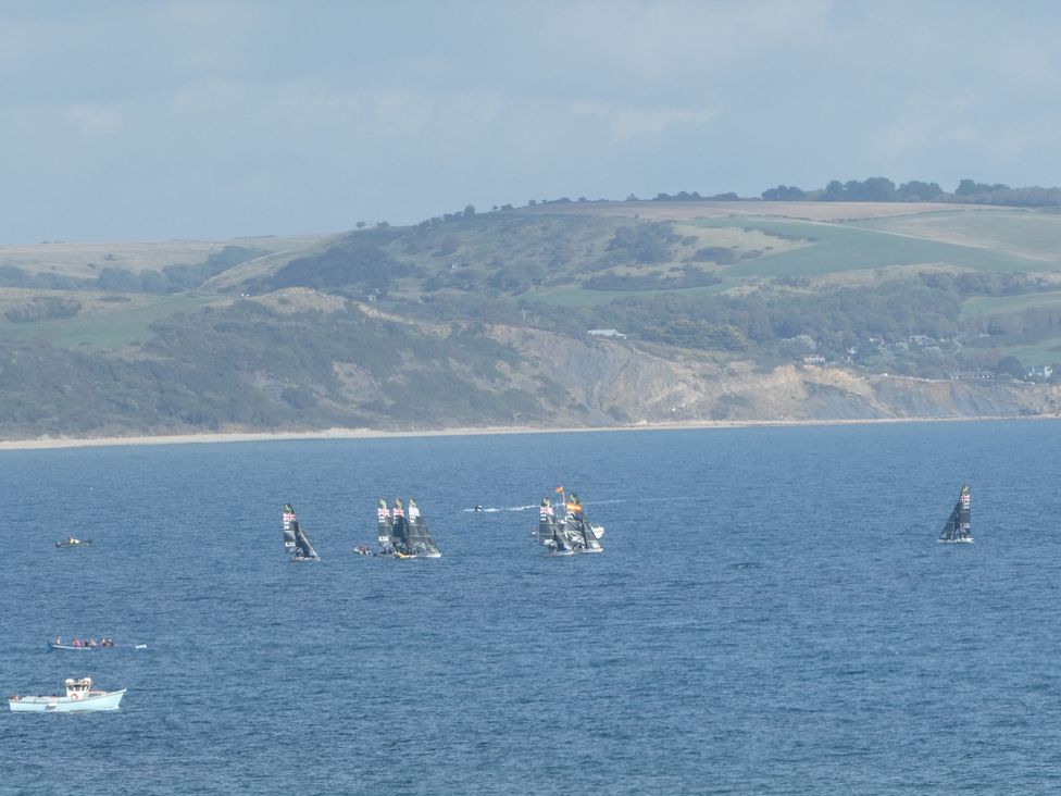 A view of sailing boats on water with hills in the background at Coast Path Cottage Weymouth