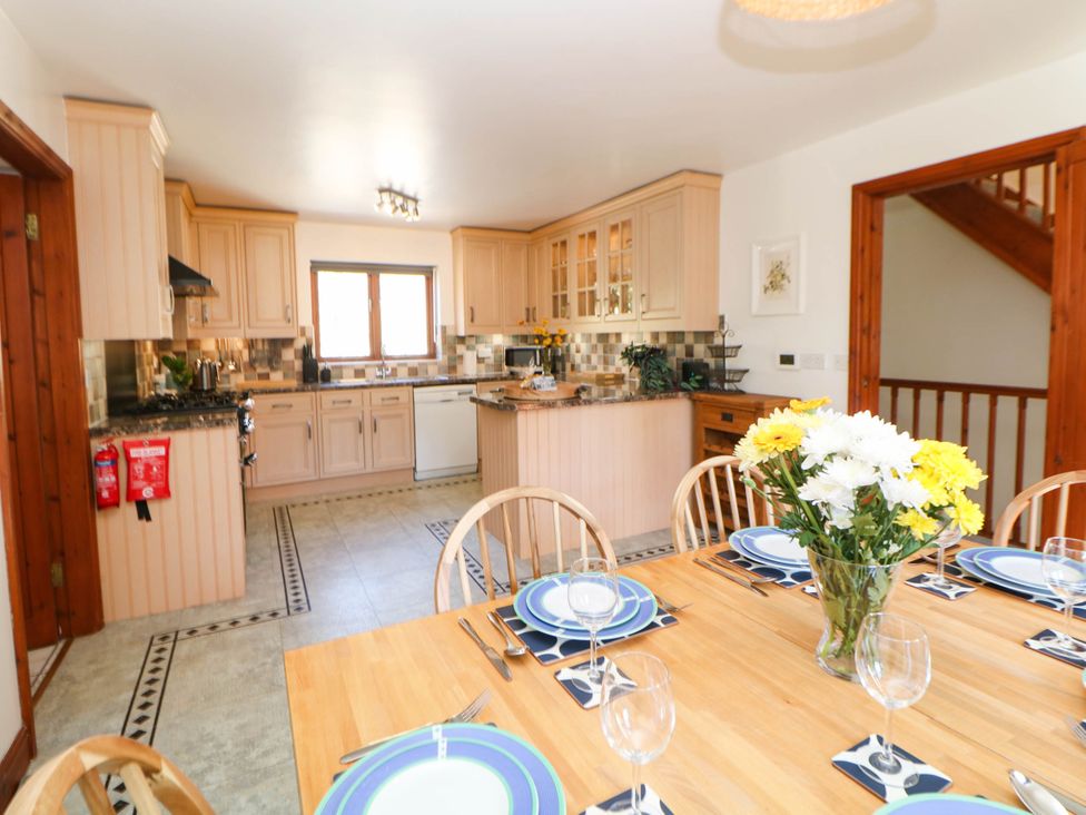 A kitchen with wooden cabinets and a dining table at Stone Lily Cottage