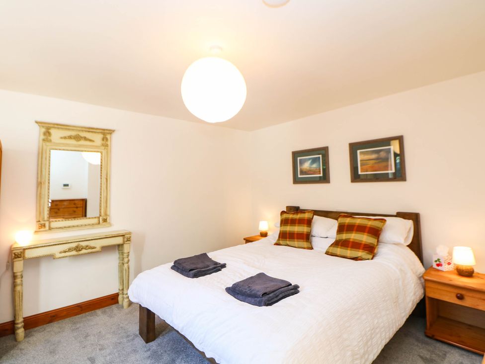 A bedroom with a bed and mirrors at Stone Lily Cottage