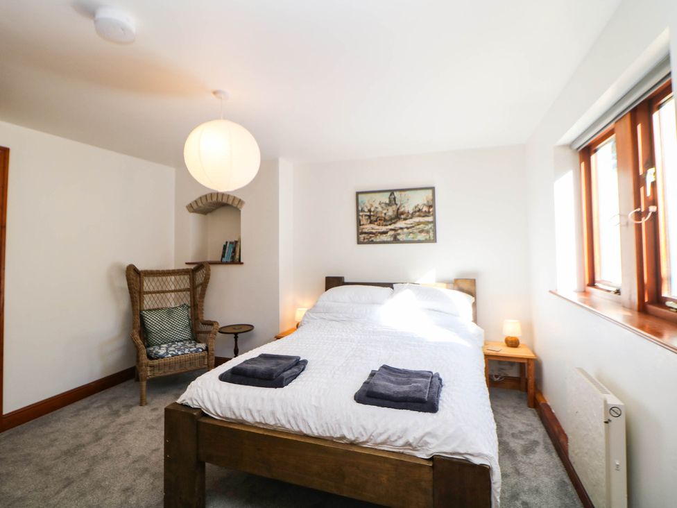 A bedroom with a bed and a chair at Stone Lily Cottage