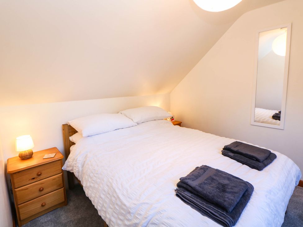A bedroom with a bed and nightstand at Stone Lily Cottage