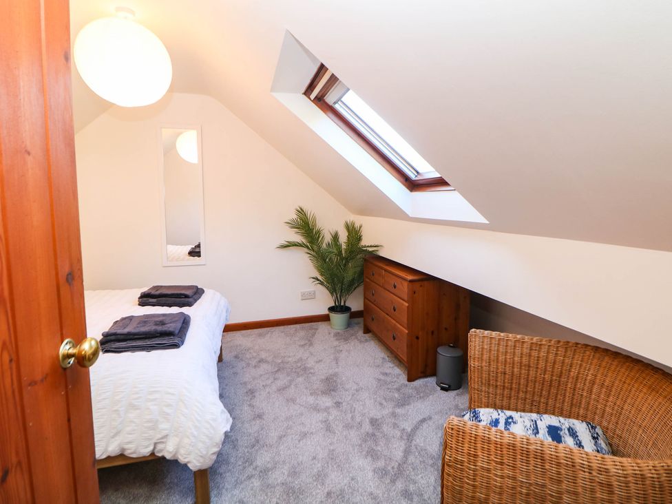 A bedroom with a bed, dresser, and chair at Stone Lily Cottage