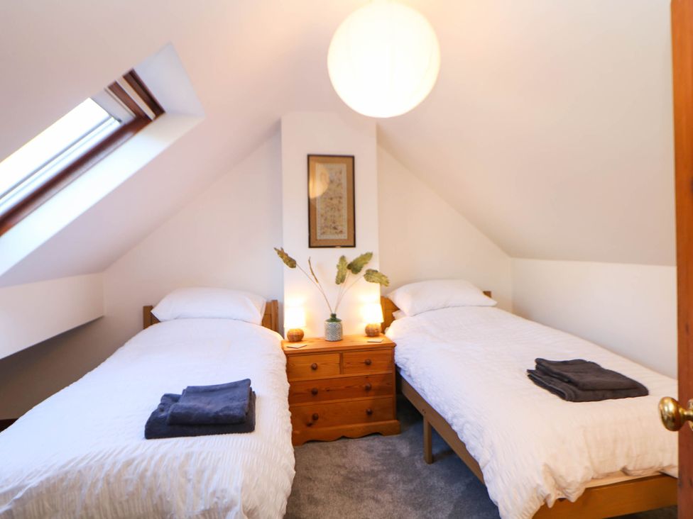 A bedroom with two beds and a dressing table at Stone Lily Cottage