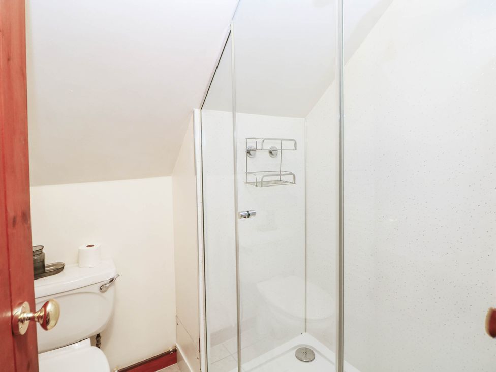 A bathroom featuring a shower, toilet, and shelves at Stone Lily Cottage