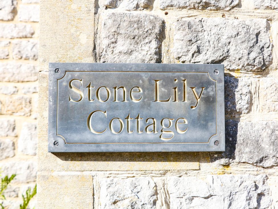 A sign for Stone Lily Cottage on a stone wall
