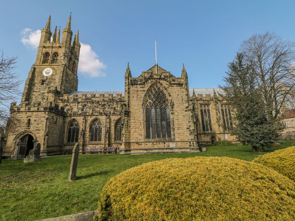 A church building with a tower and clock surrounded by bushes and grass