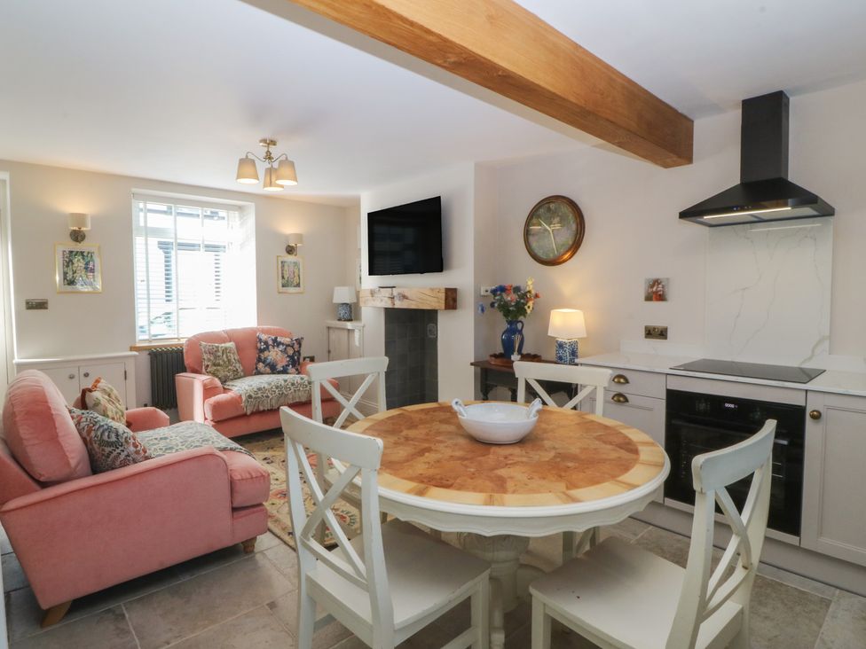 A living room with a dining area and kitchen equipment at Foxglove Cottage in Conwy