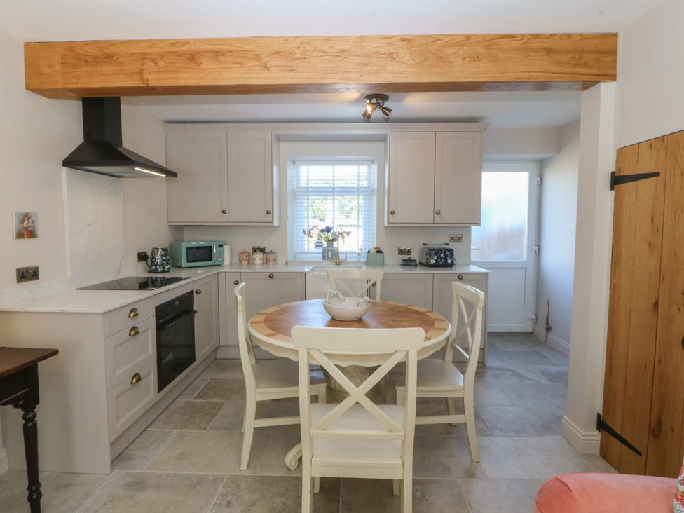 A kitchen with cabinets and a dining table at Foxglove Cottage in Conwy