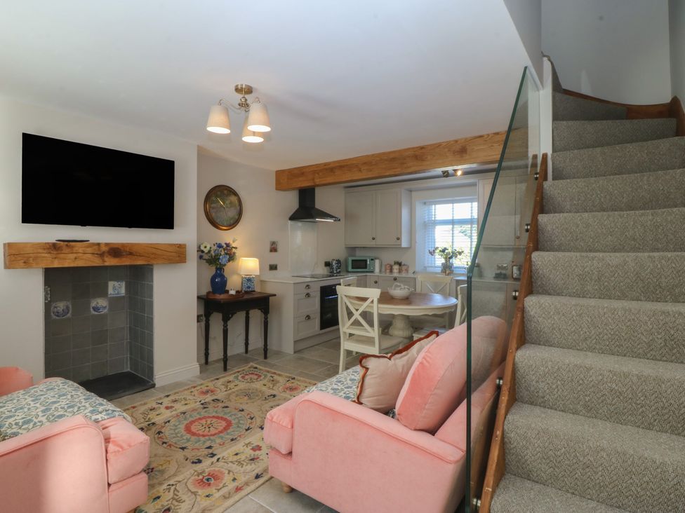 A living room with a sofa and staircase at Foxglove Cottage in Conwy