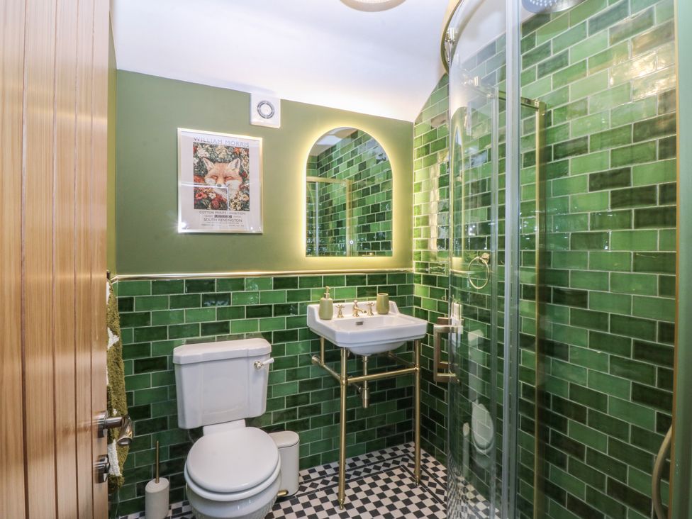 A bathroom with green tiles and fixtures at Foxglove Cottage in Conwy