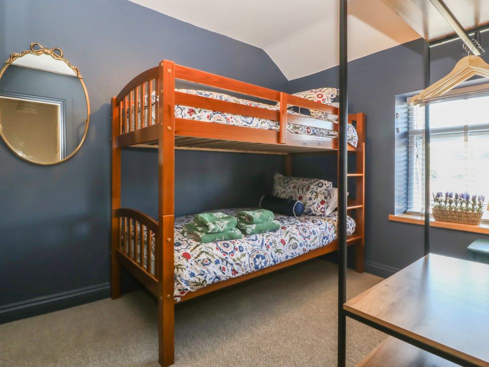 A bedroom with a bunk bed and window at Foxglove Cottage in Conwy