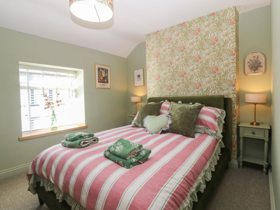 A bedroom with a bed and nightstand at Foxglove Cottage in Conwy