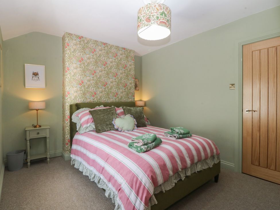 A bedroom with a bed and nightstand at Foxglove Cottage in Conwy