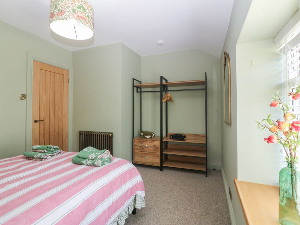 A bedroom with a bed and wardrobe at Foxglove Cottage in Conwy