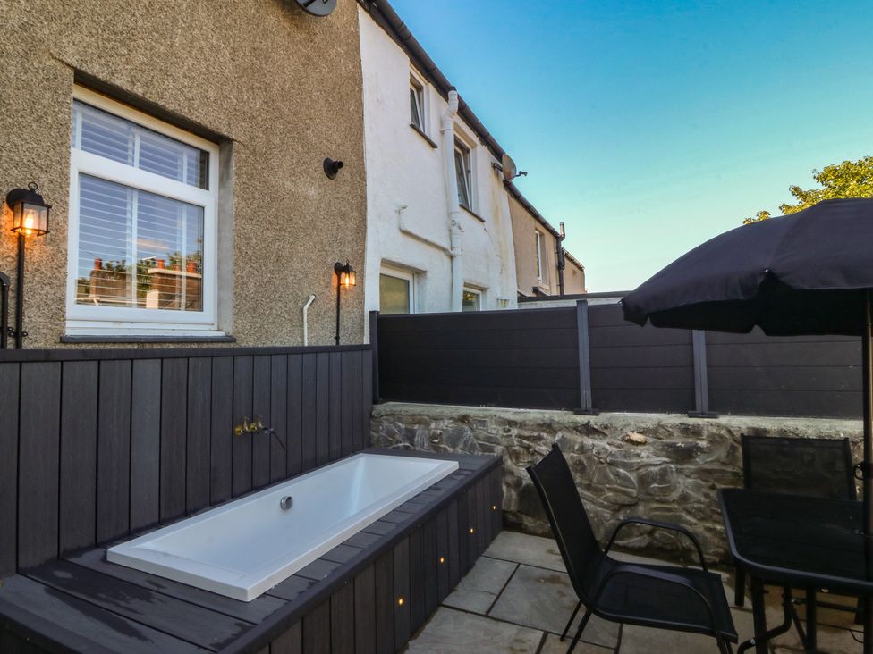 An outdoor area with a bath, seating and a stone wall at Foxglove Cottage, Conwy