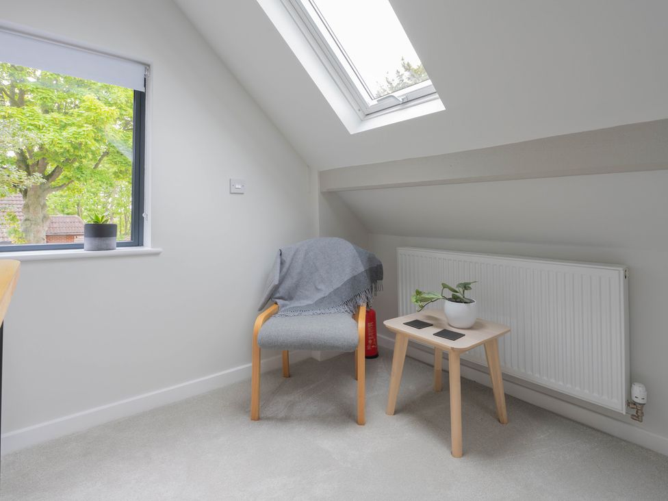 A chair with a blanket and a table in an attic at Blackwood in Hornsea