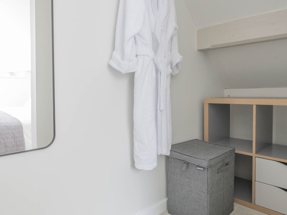 A dressing area with a robe hanging next to a mirror at Blackwood in Hornsea