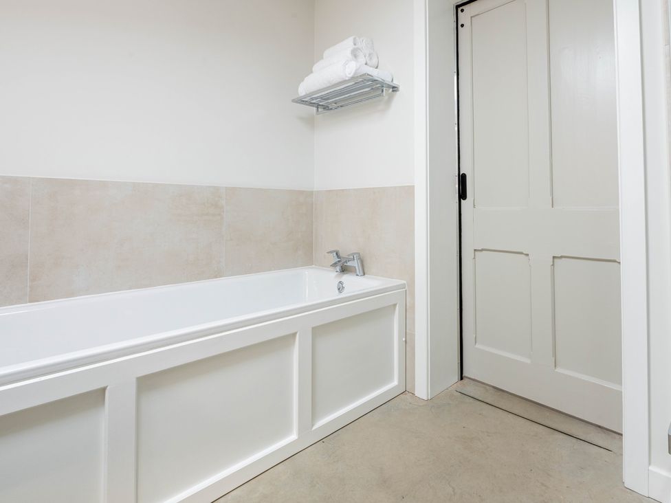 A bathroom with a bathtub and towels on a shelf at Blackwood in Hornsea