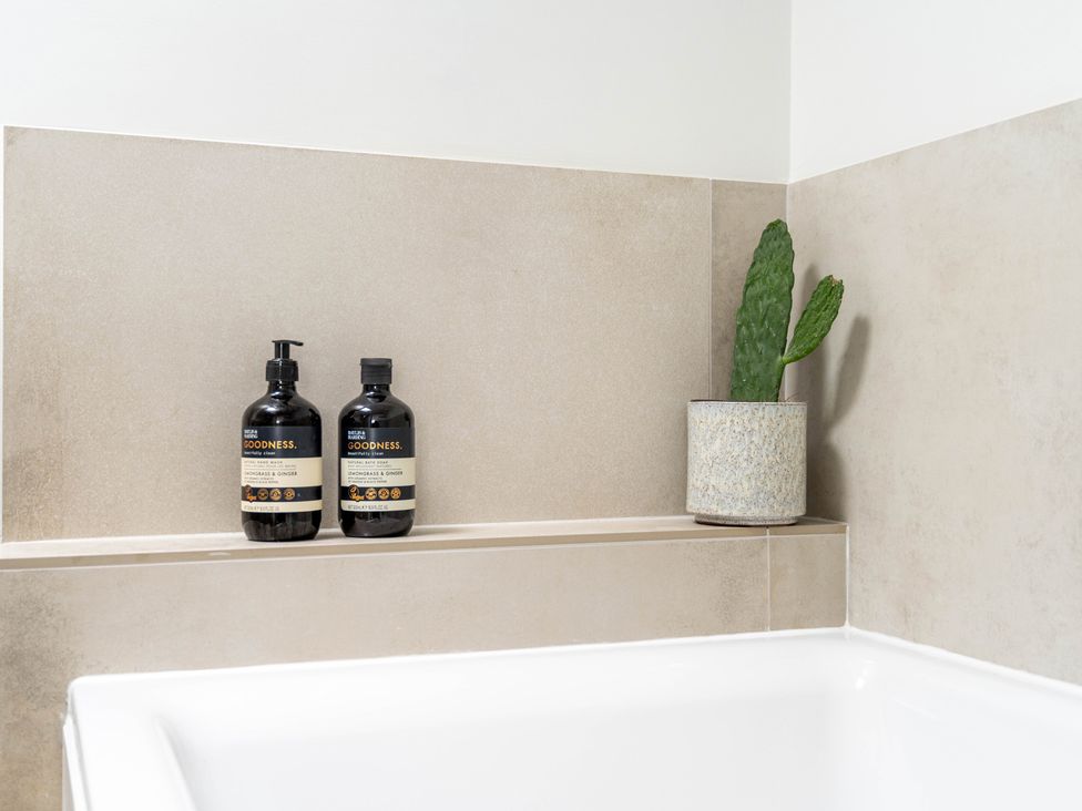A bathroom with bottles on a shelf and a potted plant at Blackwood in Hornsea