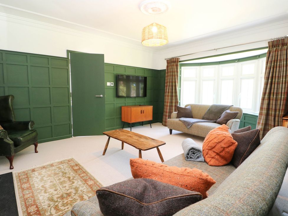 A living room with a sofa, armchair, and coffee table at Cree Cottage