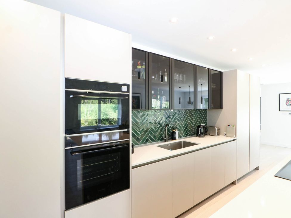 A kitchen featuring an oven, sink and wall-mounted cabinets at Cree Cottage