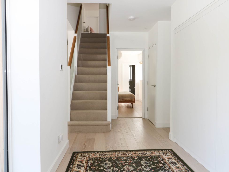 A hallway with a staircase and a door leading to a bedroom at Cree Cottage