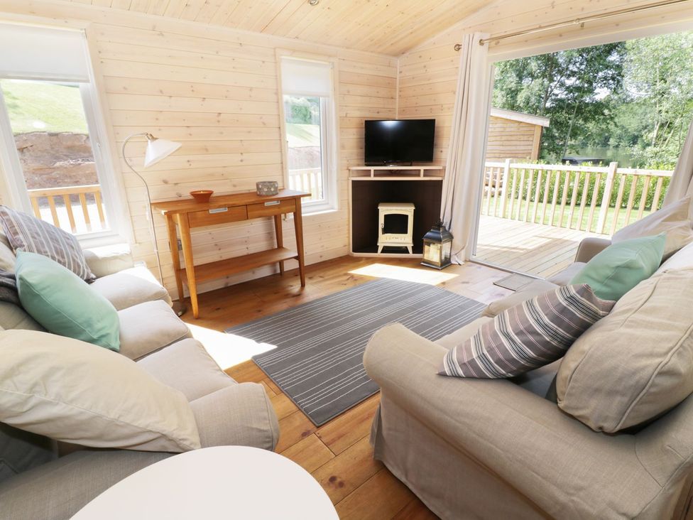 A living room with a television and a wooden table at Kingfisher in Ross-on-Wye
