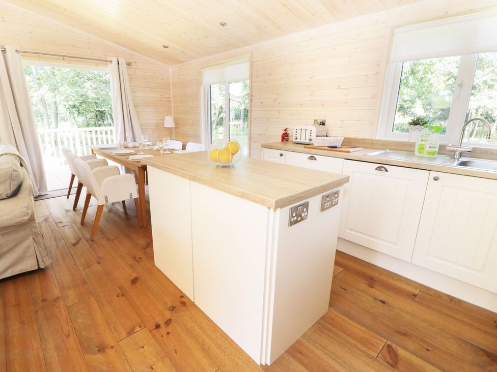 A kitchen with an island and dining table at Kingfisher in Ross-on-Wye